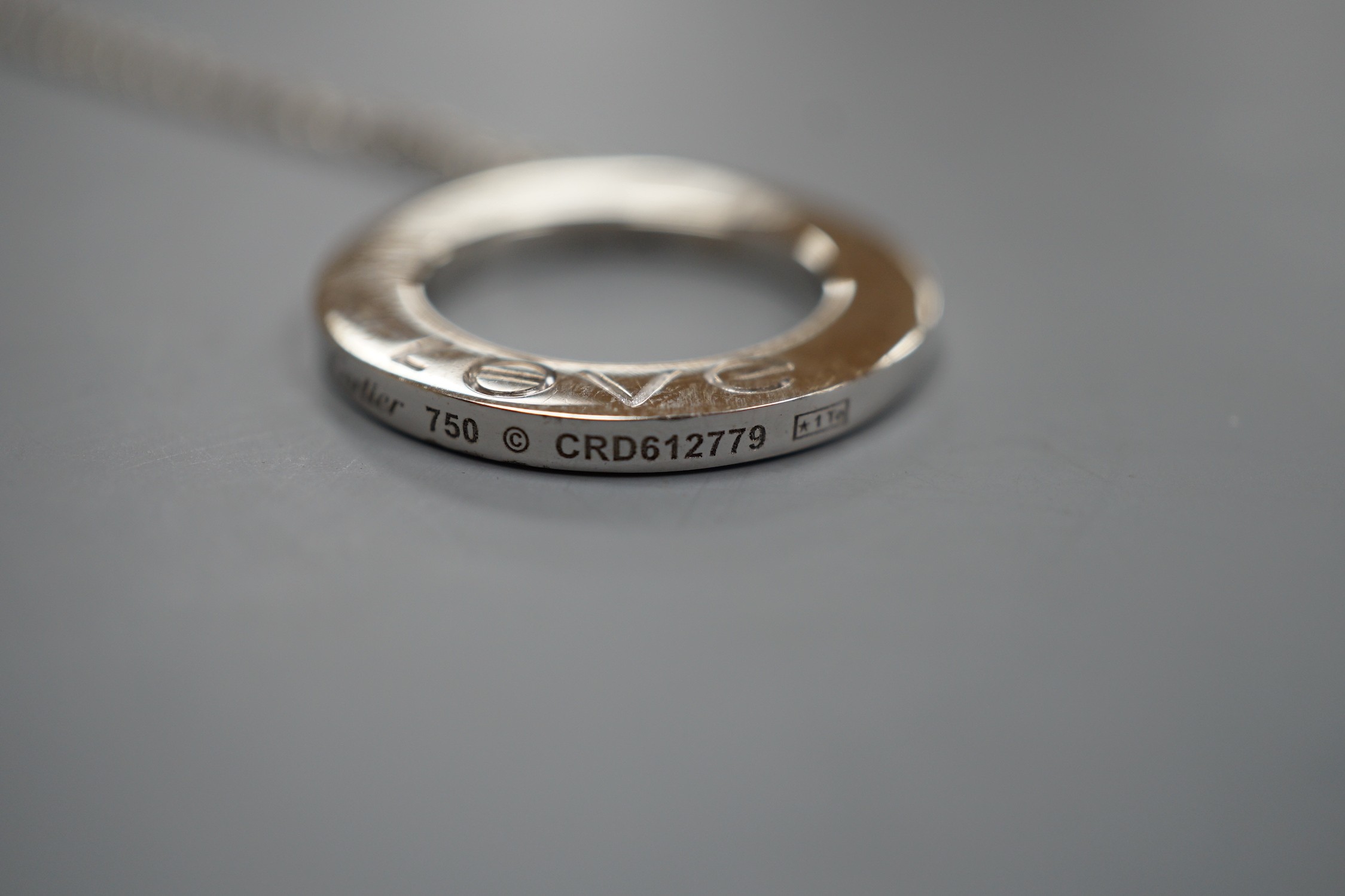 A modern Italian Cartier 750 white metal 'Love' circular pendant, 24mm, numbered CRD612779, on a 750 white metal fine link chain, 46cm, 10.8 grams.